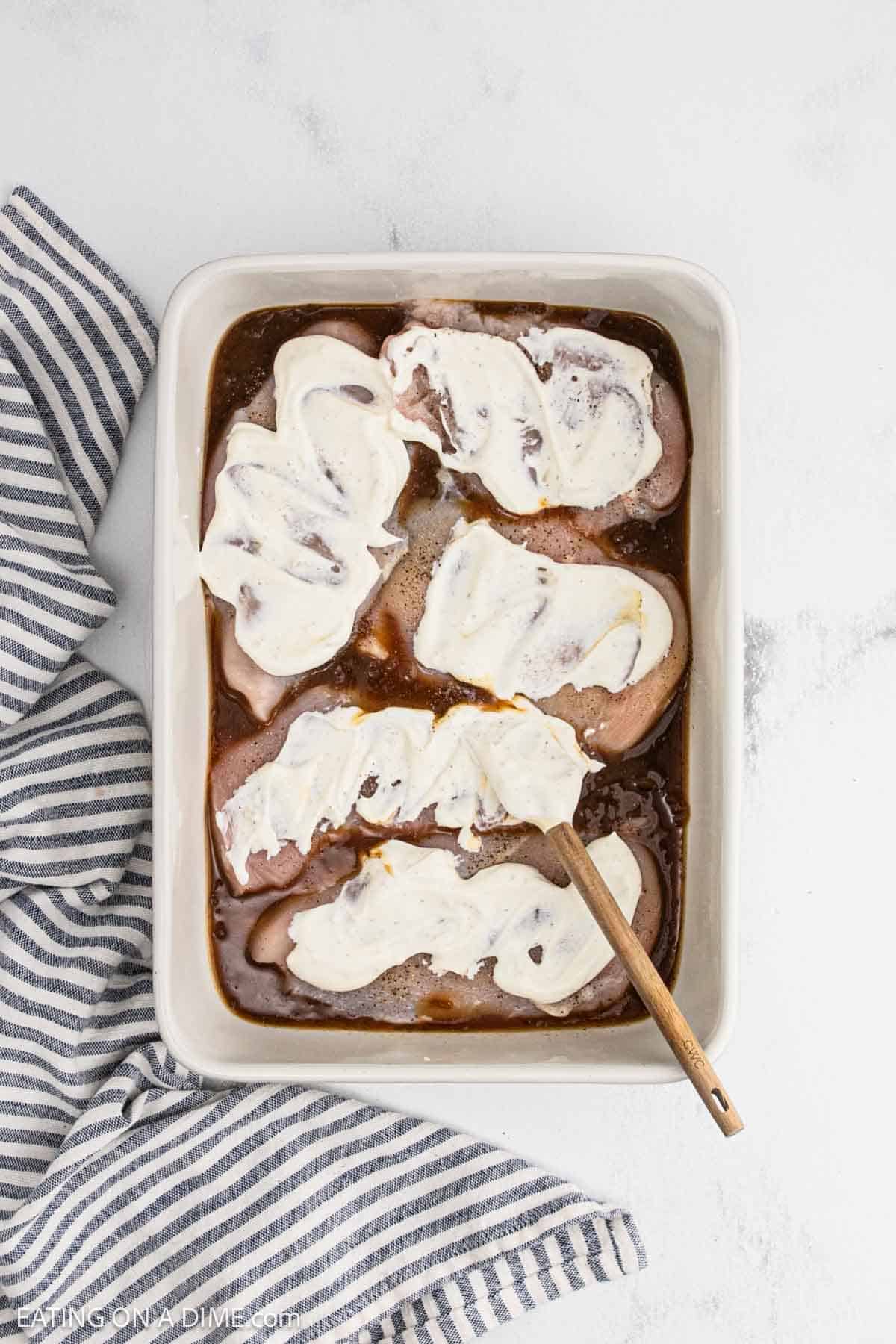 French onion dip spread over the chicken breasts that are in the baking dish.