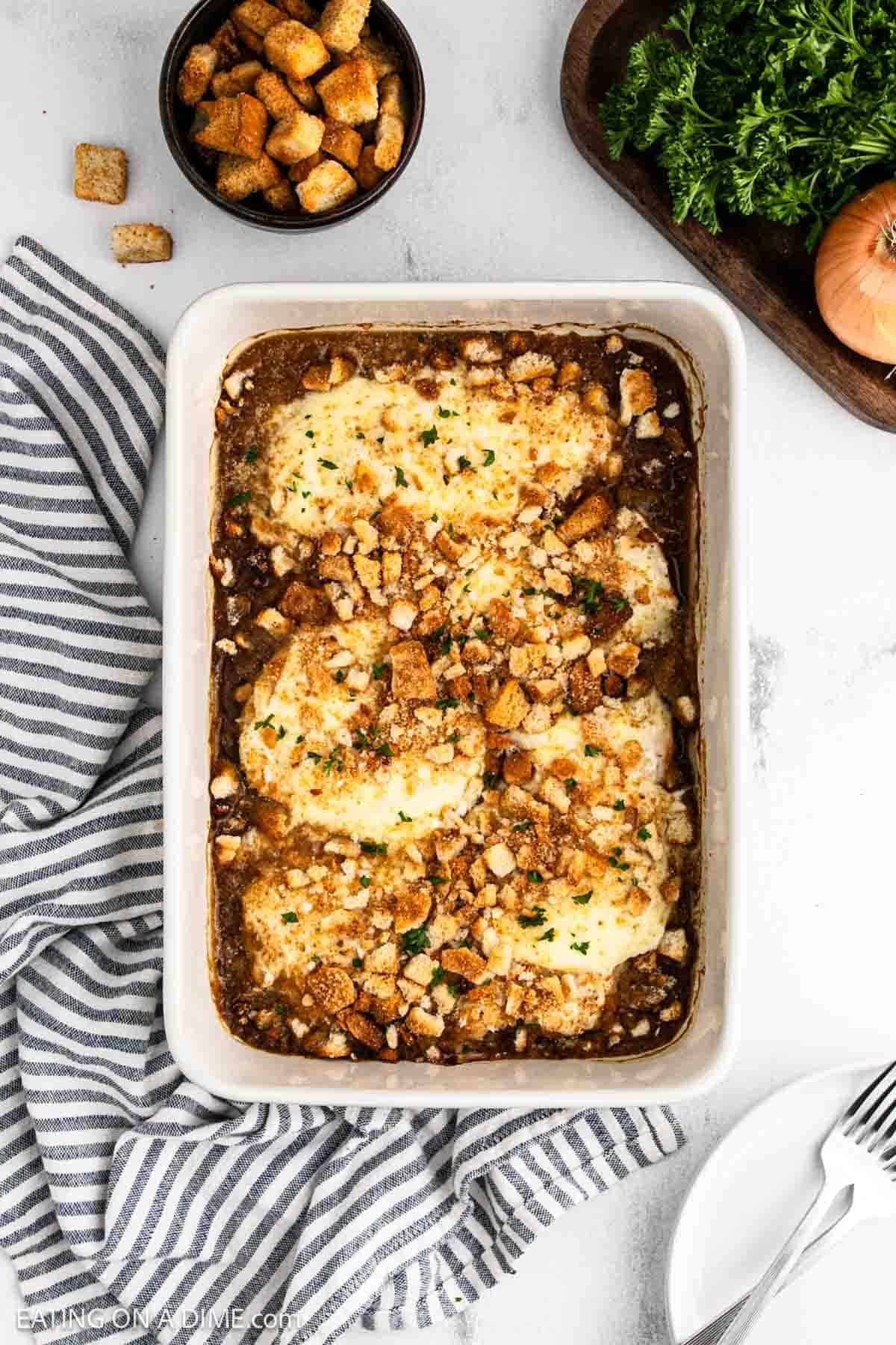 Baked chicken topped crushed croutons in a baking dish.