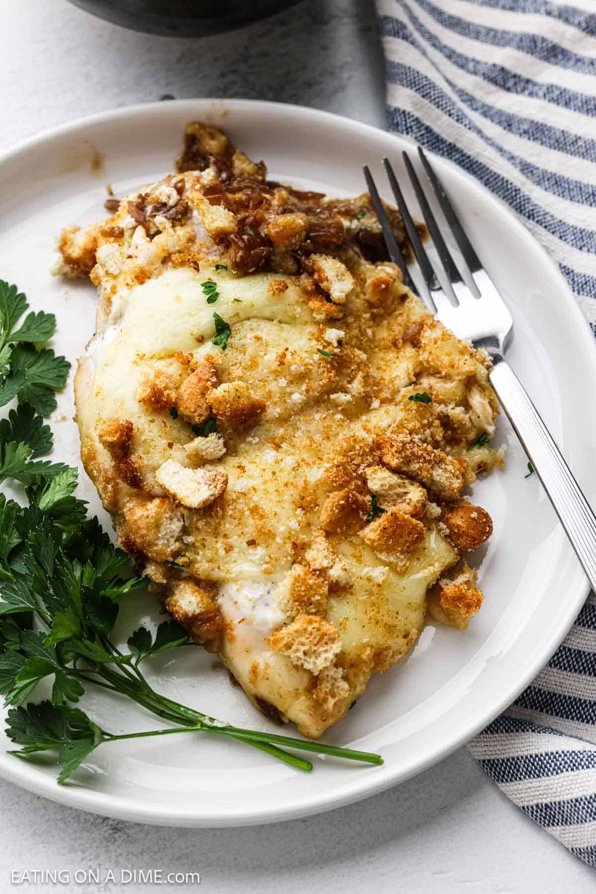 A serving of chicken breasts topped with melted cheese and crushed croutons on a plate.