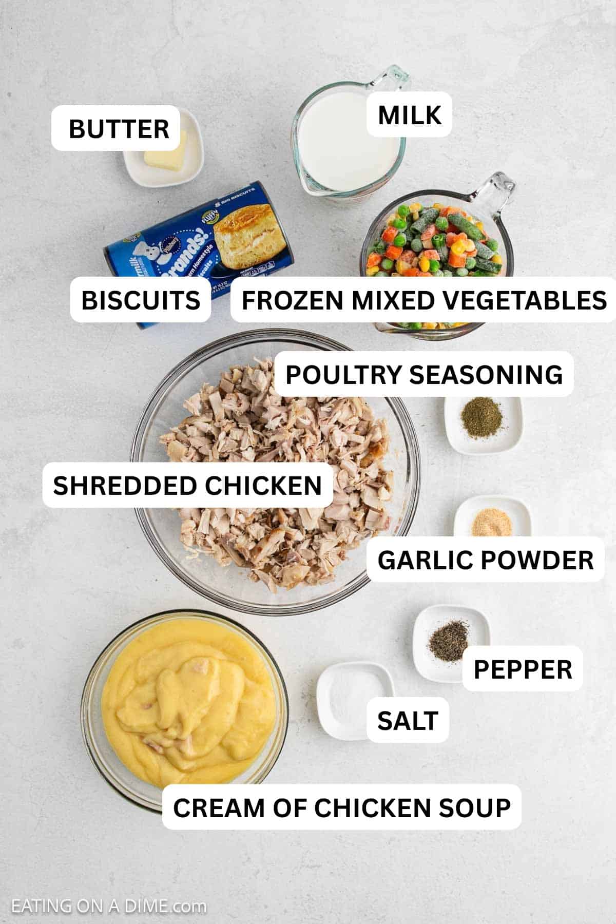 Ingredients needed to make this recipe which includes shredded chicken, cream of chicken soup, frozen veggies, canned biscuits and spices.