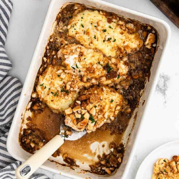 French Onion Chicken Bake in a baking dish and a serving on the spatula.