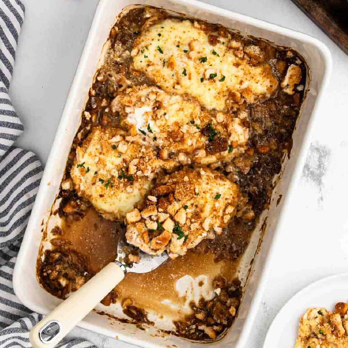 French Onion Chicken Bake in a baking dish and a serving on the spatula.