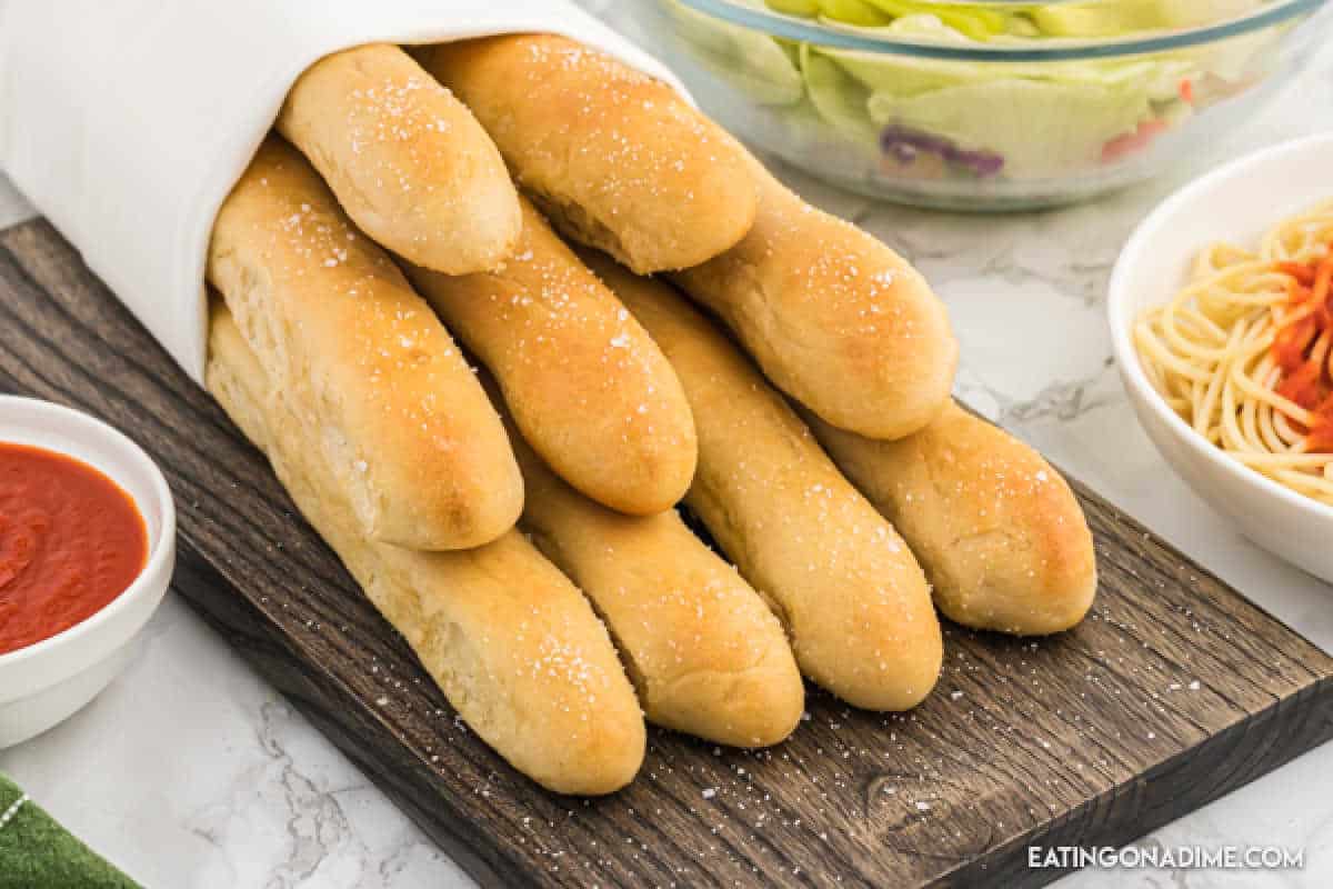 Olive Garden Breadsticks wrapped in a towel on a wooden platter.